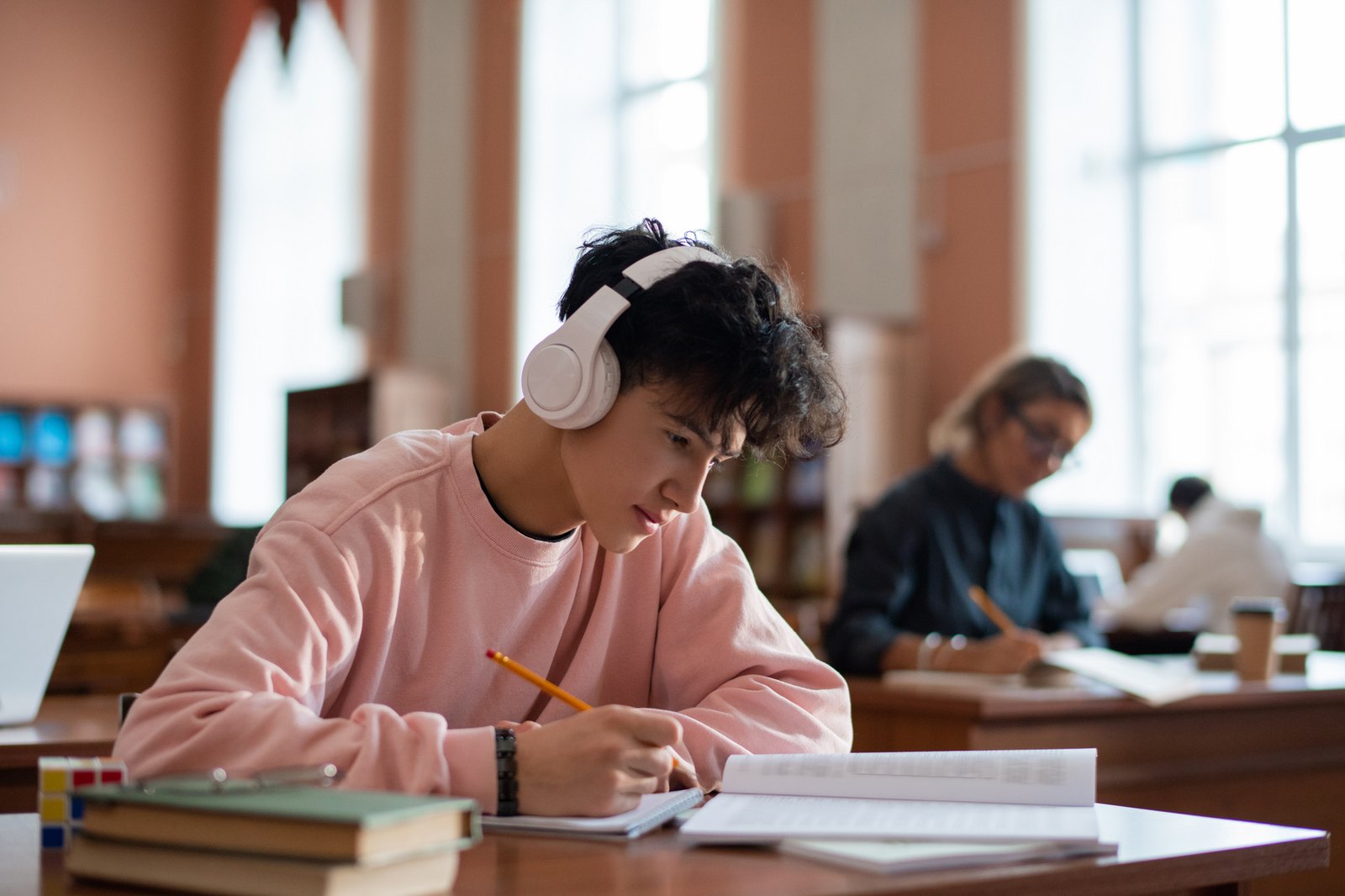 A student practising written work while studying with headphones